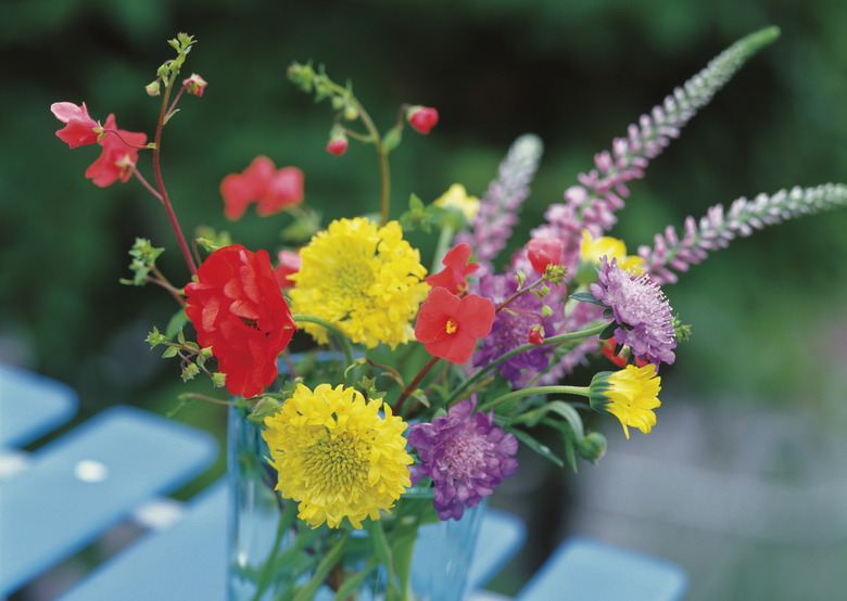 Freshly picked flowers in a vase on a table outside.