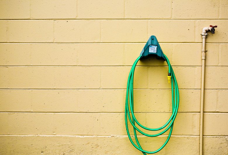 Garden hose in rack on wall with faucet