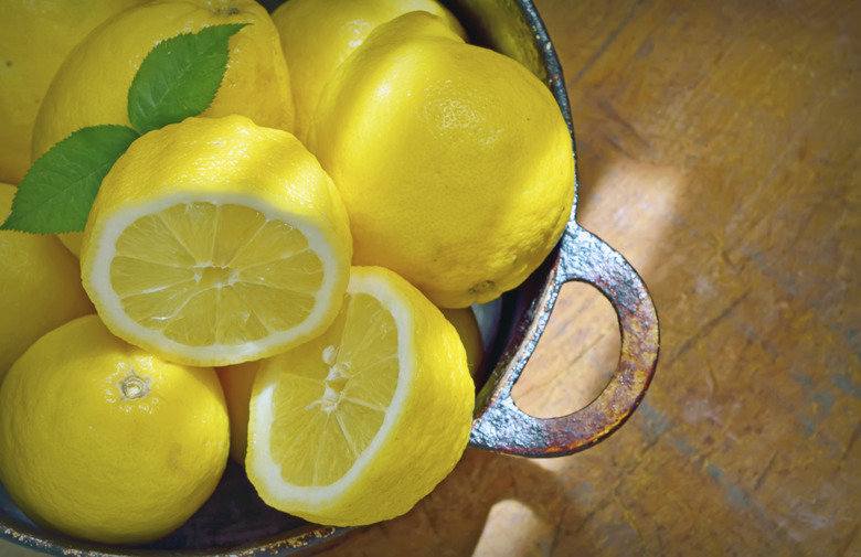 A bowl of fresh lemons on a wood table.