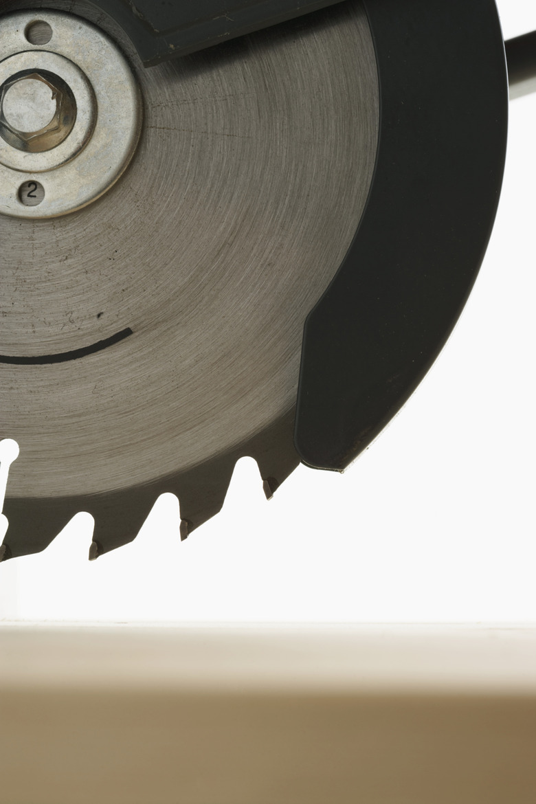 Circular saw above wooden board, close-up