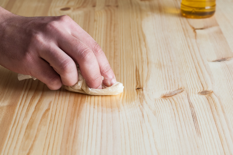 A hand rubbing finish onto wood.