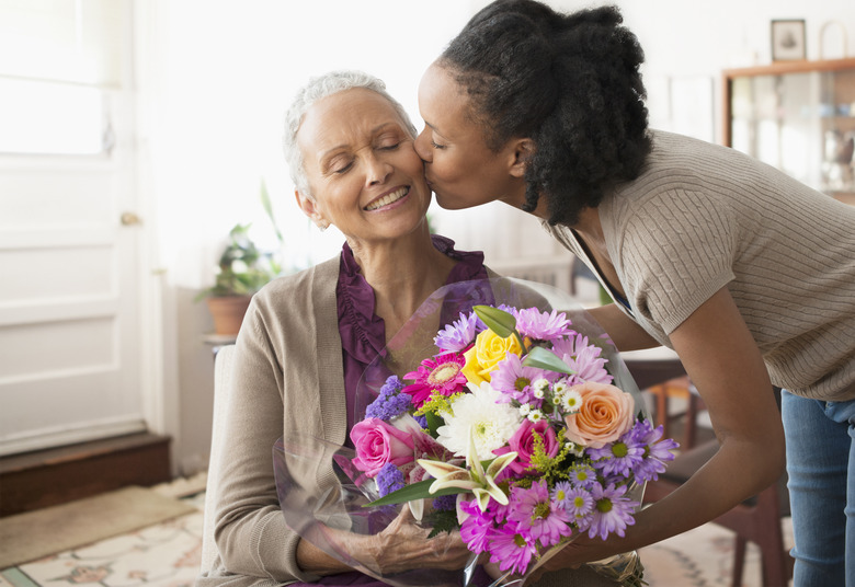 A woman giving her mother a bouquet of flowers.