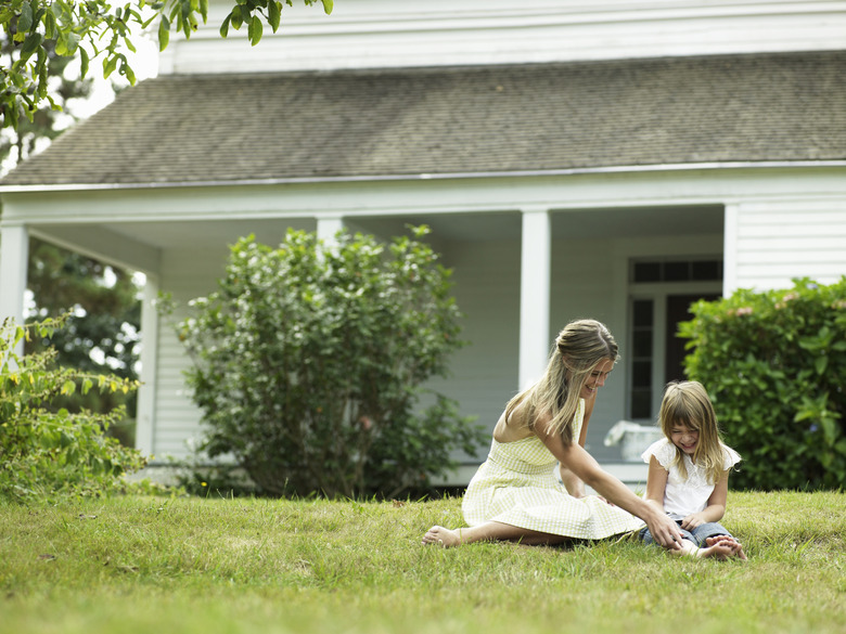 Young woman playing with daughter (4-5) on lawn outside house