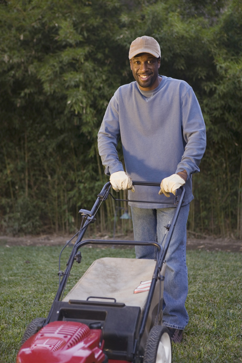 Smiling man mowing lawn