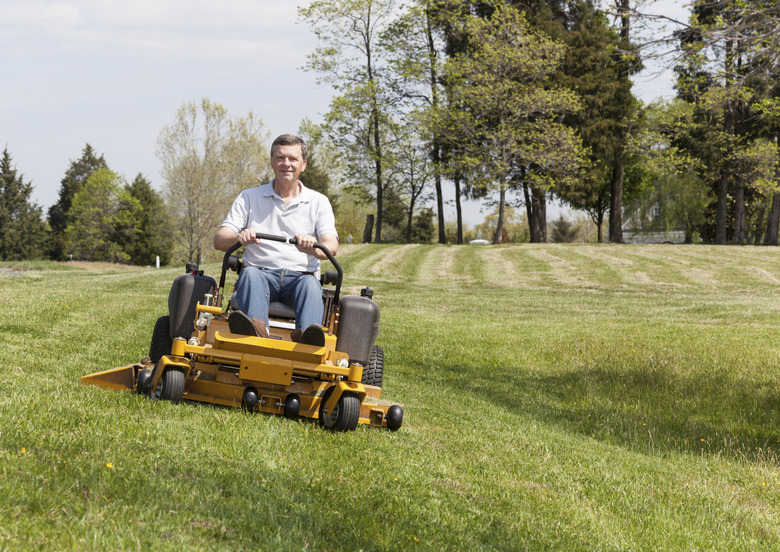 Senior man rides zero turn lawn mower on turf