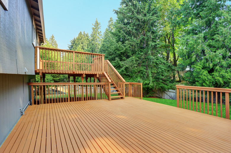 Backyard view of grey rambler house with upper and lower decks.