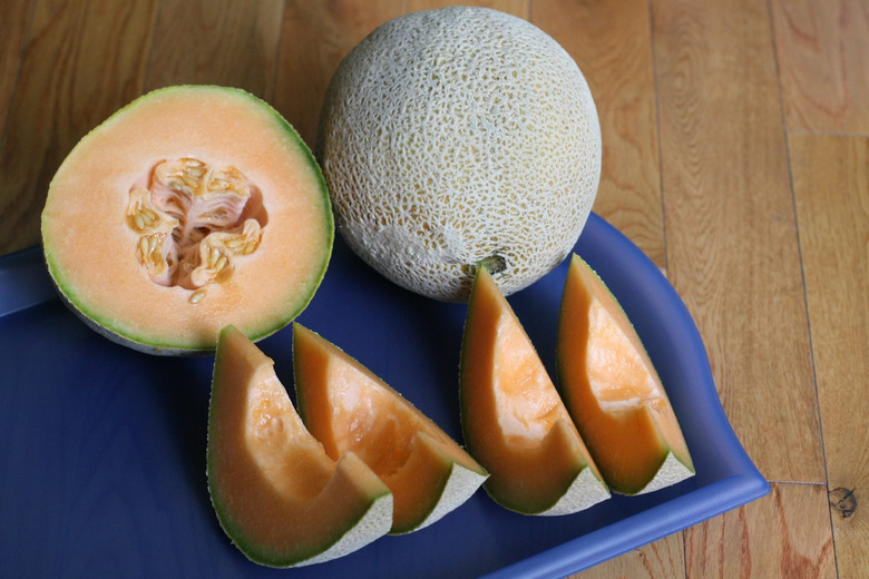 Two cantaloupes (Cucumis melo var. cantalupensis) sliced open on a cutting board.