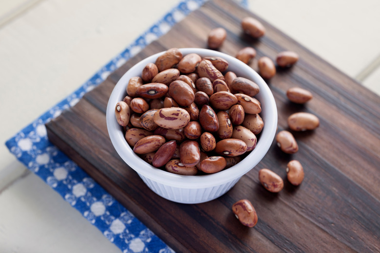 A close-up of pinto beans in a bowl on a cutting board.