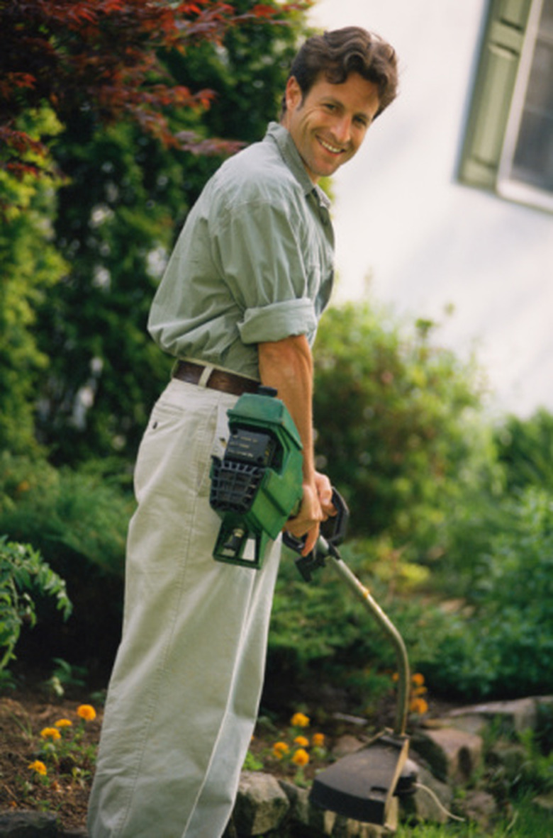 Smiling man outdoors with weed whacker