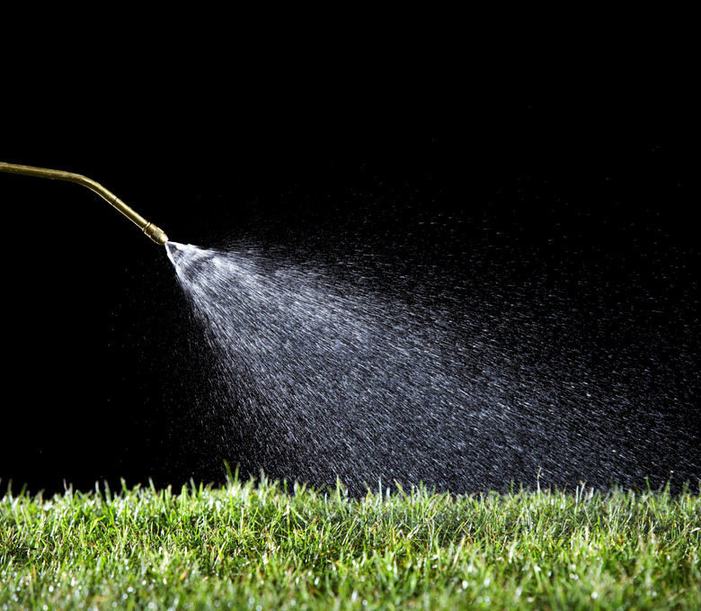 Hose watering grass on black background